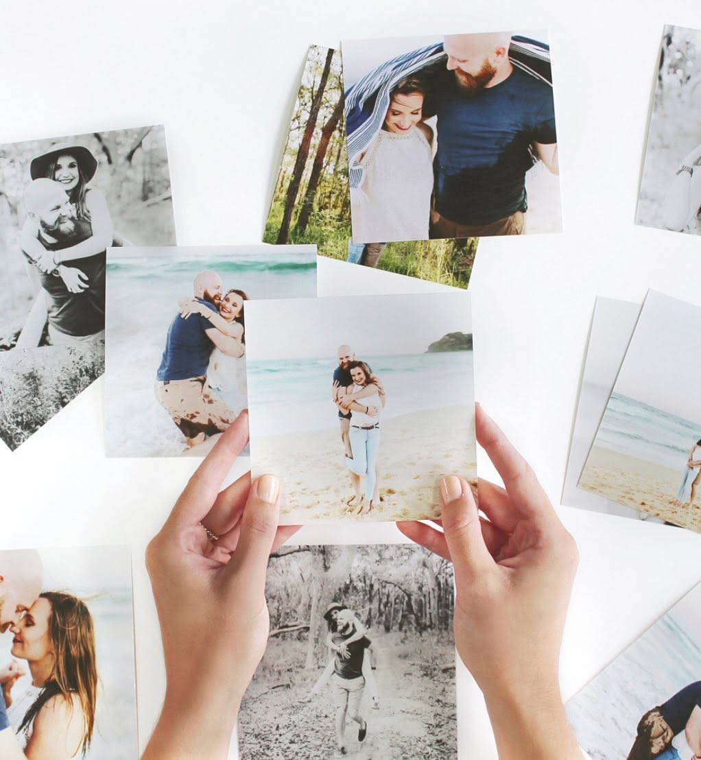 A person holding a wedding print above a collection of photographs