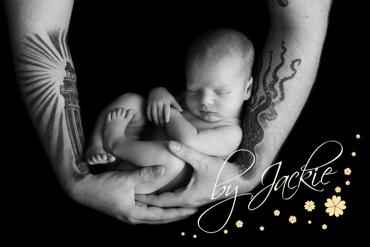 Black and white image of baby being held in parents hands. Image by Babies By Jackie Photography, specialist baby photographer in York, Leeds, Harrogate