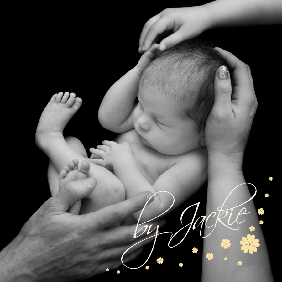 Black and white image of newborn with family's hands