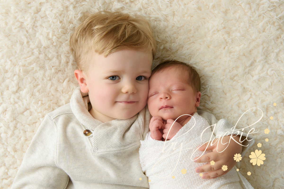 Photograph of little boy with his brand new baby sister. Sibling and newborn images by Babies By Jackie Photography, specialist baby photographer in York, Leeds, Harrogate