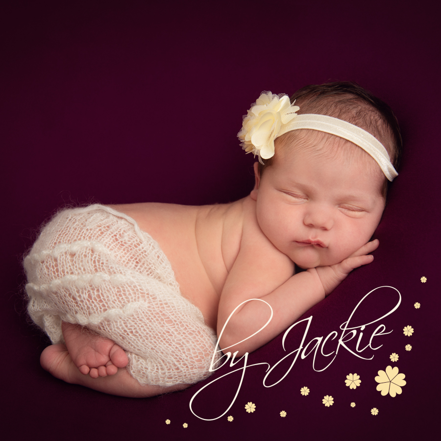 Newborn baby girl asleep on tummy in burgundy and cream photographed by Babies By Jackie Photography, specialist baby photographer in York, Leeds, Harrogate