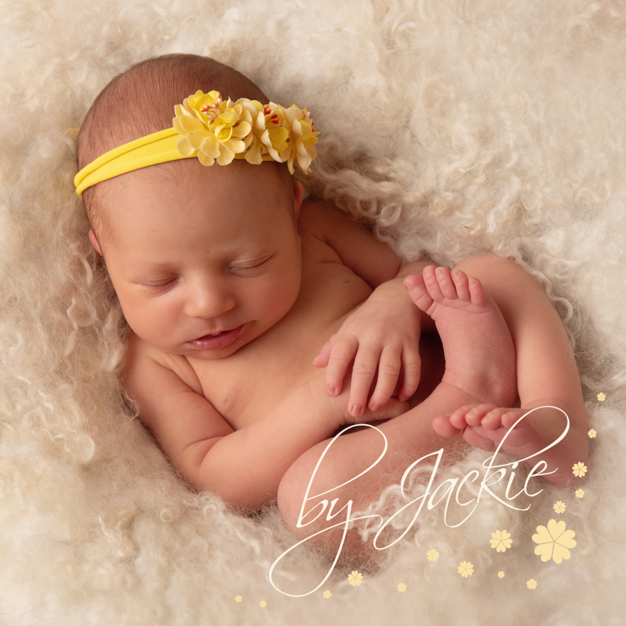 baby girl with yellow headband snuggled in cream fluff