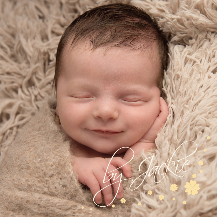 Close up image of newborn baby with a little smile by Babies By Jackie Photography