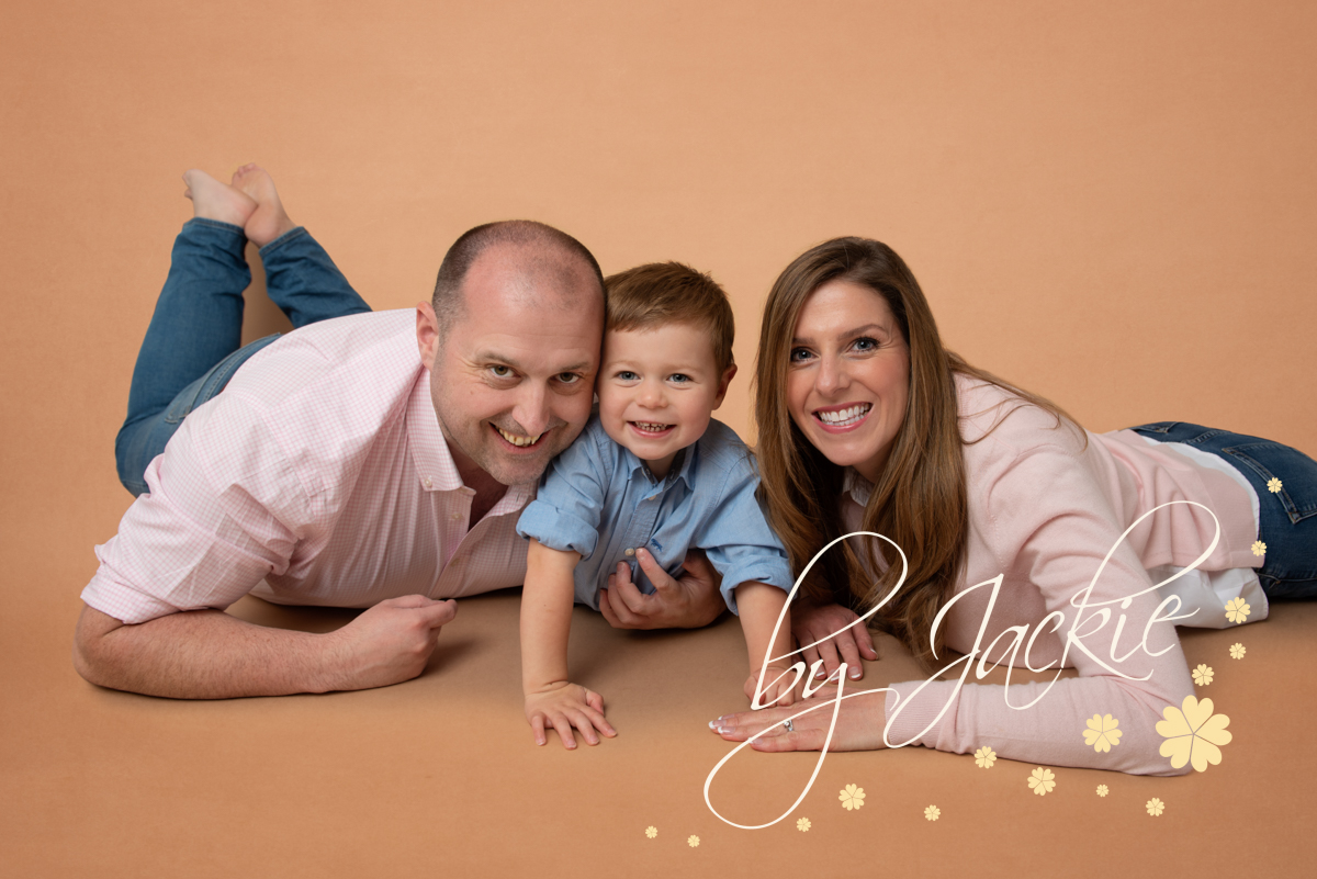 Family portrait parents and young child lying down on their tummies