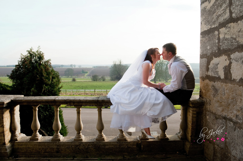 Photo of bride and groom kissing seated on a wall outside Hazlewood Castle, near York and Leeds. Image copyright By Jackie Photography, Selby