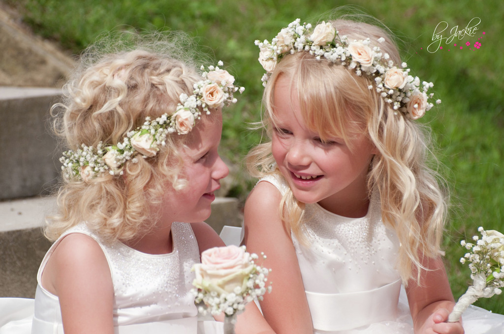 Photo of two flower girls or bridesmaids with flowers in their hair sitting on a step chatting at a wedding near Leeds. Image copyright By Jackie Photography near Howden and Goole